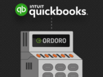 A grey and black machine with the Ordoro name and logo in the screen. Above the machine says "Intuit Quickbooks" with a line connecting the two.